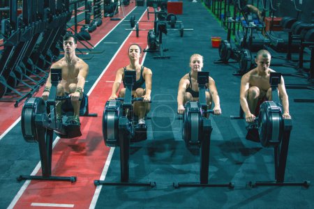 Foto de Grupo de deportistas haciendo ejercicio en los remeros del gimnasio - Imagen libre de derechos