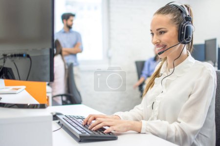 Téléchargez les photos : Agent de service à la clientèle féminin utilisant l'ordinateur dans le bureau - en image libre de droit