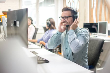 Photo for Dispatcher listening to a client using hands-free headset at his workplace in call center - Royalty Free Image