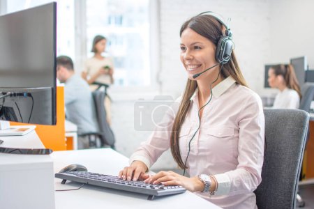 Téléchargez les photos : Bel opérateur de service à la clientèle dans le casque travaillant dans le centre d'appels - en image libre de droit
