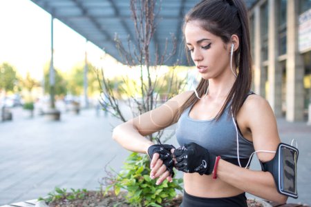 Téléchargez les photos : Jeune femme se préparant pour la course d'entraînement et de mettre ses gants de sport - en image libre de droit