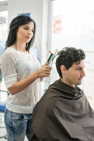 Téléchargez les photos : Coiffeur couper les cheveux des clients dans le salon de coiffure - en image libre de droit