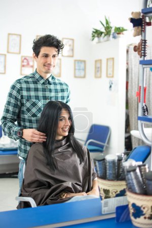 Spiegelbild des Friseurs Friseur mit Kamm kämmende Haare der weiblichen Kundin. Frau im Friseursalon.