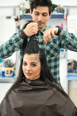 Téléchargez les photos : Jeune homme coiffeur coupe les cheveux des clients avec des ciseaux au salon de coiffure - en image libre de droit