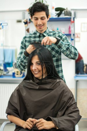 Photo for Male hairdresser makes hairstyle for a girl at hair salon - Royalty Free Image