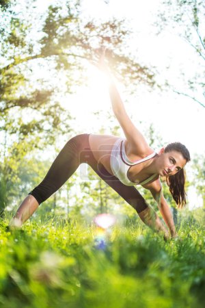 Téléchargez les photos : Femme faisant de l'exercice dans le parc au coucher du soleil - en image libre de droit