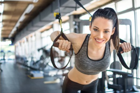 Foto de Mujer deportiva haciendo ejercicios TRX con correas de suspensión en el gimnasio. - Imagen libre de derechos