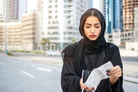 Foto de Mujer árabe en bancarrota infeliz en Abaya con cartera vacía en la calle - Imagen libre de derechos