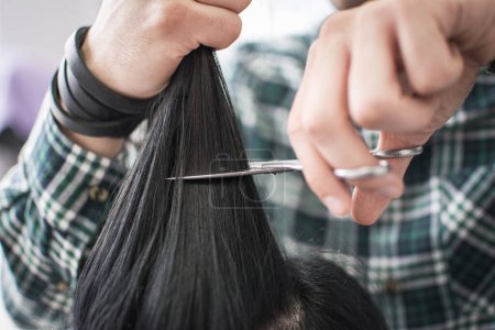 Foto de Primer plano de un peluquero masculino cortando el pelo de los clientes con tijeras en el salón de belleza - Imagen libre de derechos