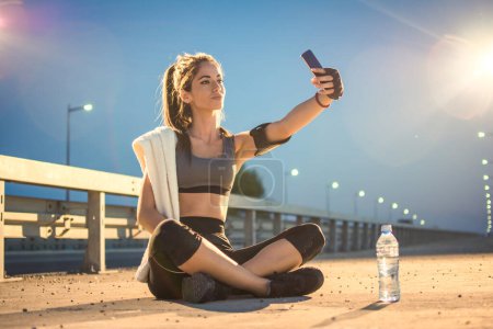 Téléchargez les photos : Belle sportive souriante prenant un selfie après l'entraînement à l'extérieur - en image libre de droit