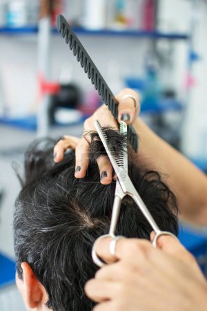 Imagen de cerca de peluquero recortando el pelo negro con tijeras