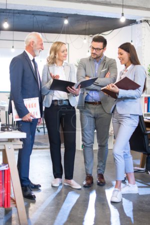 Photo for Group of mixed age business people analyzing documents together on meeting in office - Royalty Free Image
