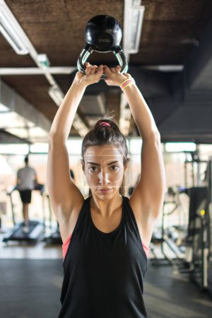 Photo for Attractive sporty girl doing exercises with kettlebell in a gym - Royalty Free Image