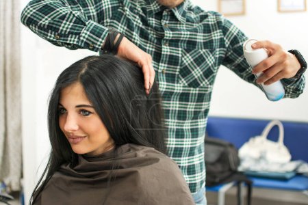 Photo for Male hairdresser applying spray on clients hair at hair in salon - Royalty Free Image