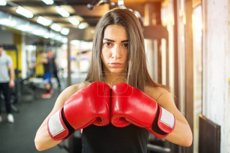 Téléchargez les photos : Jeune fille de fitness avec des gants de boxe dans la salle de gym - en image libre de droit