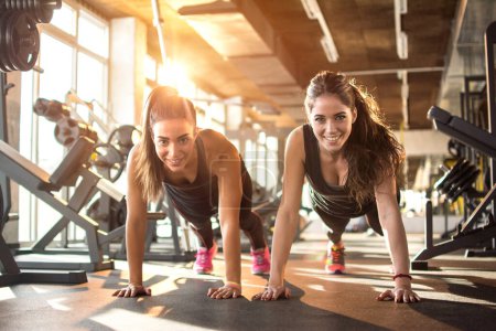 Photo for Two sporty girls doing push ups in gym - Royalty Free Image
