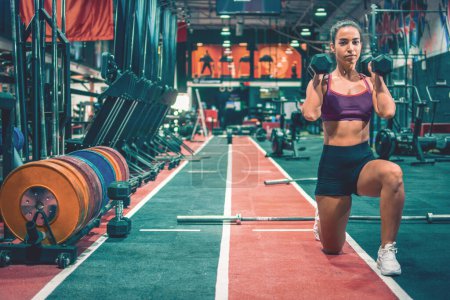 Téléchargez les photos : Fitness sportive effectuant des fentes avec haltères dans la salle de gym - en image libre de droit
