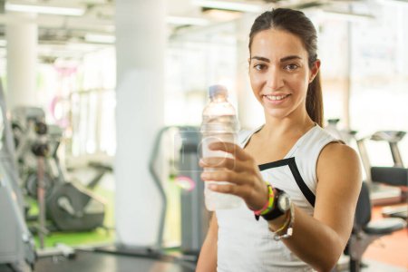 Foto de Mujer en forma sosteniendo una botella de agua en un gimnasio - Imagen libre de derechos