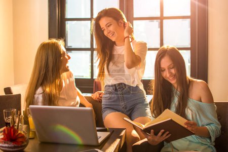 Téléchargez les photos : Groupe de trois adolescentes faisant une pause dans leurs études à la maison - en image libre de droit