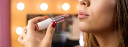 Photo for Close up portrait of attractive girl applying lipstick on her lips. Panoramic view. - Royalty Free Image
