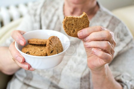 Photo for Close up of senior womans hands holding cookies. - Royalty Free Image