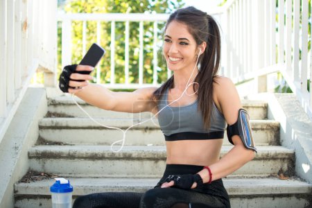 Téléchargez les photos : Souriant fille sportive prenant un selfie avec téléphone mobile à l'extérieur. - en image libre de droit