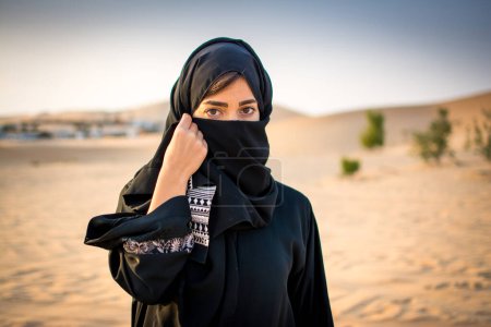 Photo for Portrait of beautiful Muslim woman wearing traditional Arabian clothing in the desert. - Royalty Free Image