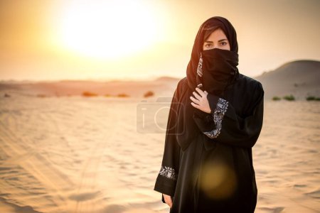 Porträt einer schönen arabischen Frau in der Wüste bei Sonnenuntergang.