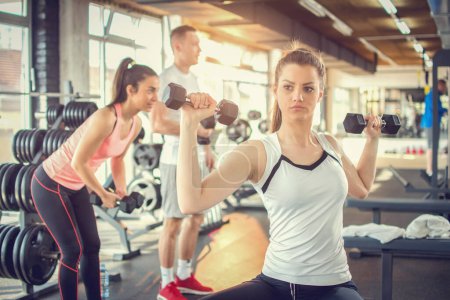 Photo for Young woman lifting dumbbells at the gym. - Royalty Free Image