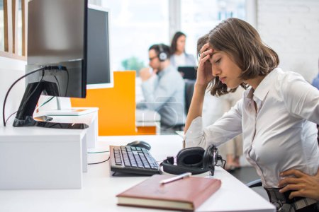 Téléchargez les photos : Jeune femme d'affaires souffrant de maux de tête devant l'ordinateur au bureau. - en image libre de droit