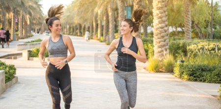 Foto de Dos jóvenes mujeres deportivas corriendo juntas al aire libre - Imagen libre de derechos