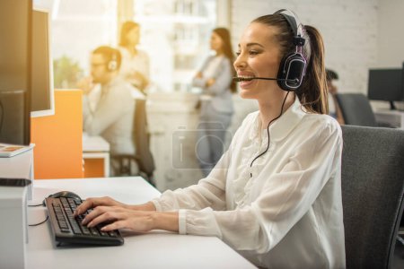 Photo for Smiling female helpline operator with headset in call center. - Royalty Free Image