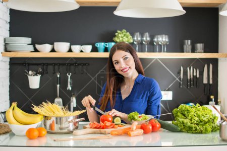 Photo for Young woman cutting vegetables in kitchen at home - Royalty Free Image