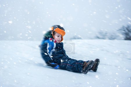 Foto de Chico excitado bajando en trineo en un día nevado - Imagen libre de derechos
