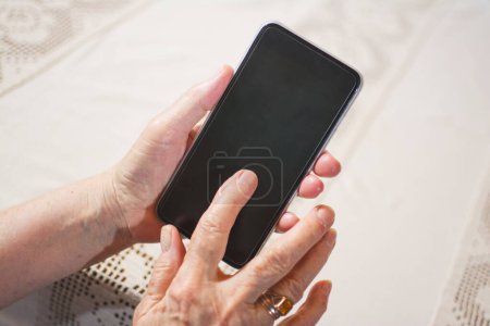 Téléchargez les photos : Gros plan d'un doigt ridé touchant un smartphone - en image libre de droit