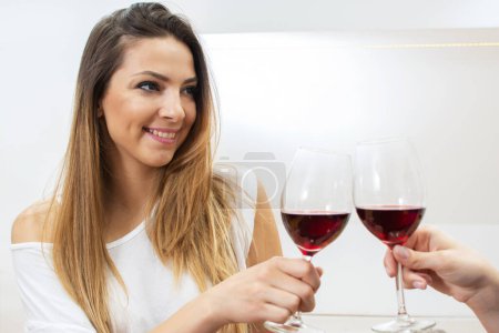 Photo for Portrait of young woman clinking glasses of red wine - Royalty Free Image