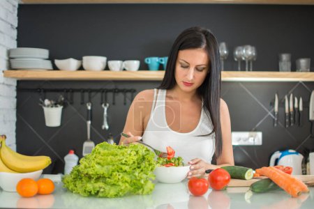 Photo for Young woman eating a healthy salad in kitchen - Royalty Free Image