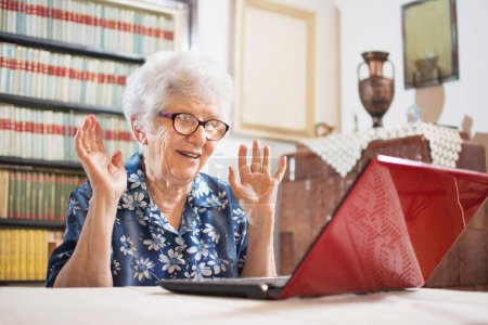 Photo for Surprised senior woman sitting in front of laptop at home - Royalty Free Image