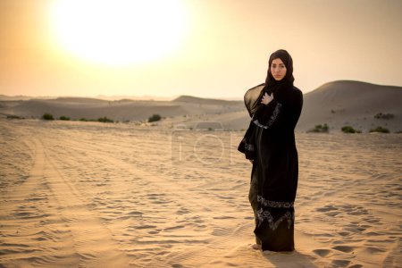 Photo for Arab woman standing in the desert during sunset. - Royalty Free Image