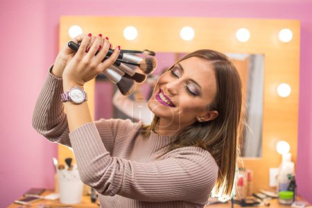 Photo for Young woman holding a lot of make-up brushes. - Royalty Free Image