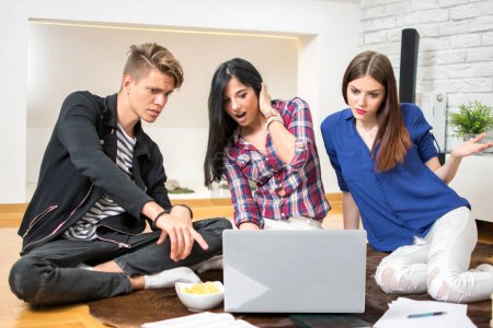 Photo for Three students using laptop while sitting on floor at home - Royalty Free Image