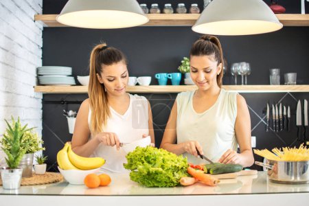 Téléchargez les photos : Jeunes sœurs jumelles préparant des aliments sains dans la cuisine - en image libre de droit