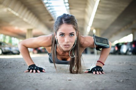 Téléchargez les photos : Femme de remise en forme faisant push-ups pendant l'entraînement cross extérieur. - en image libre de droit