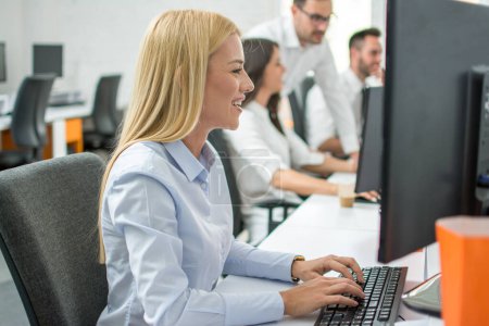 Side view of beautiful blonde hair business woman working on computer in office