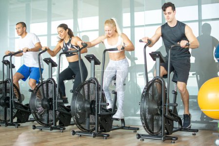 Photo for Group of young people doing exercises on elliptical machine at gym - Royalty Free Image