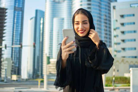 Téléchargez les photos : Moyen-Orient femme utilisant téléphone mobile à l'extérieur - en image libre de droit