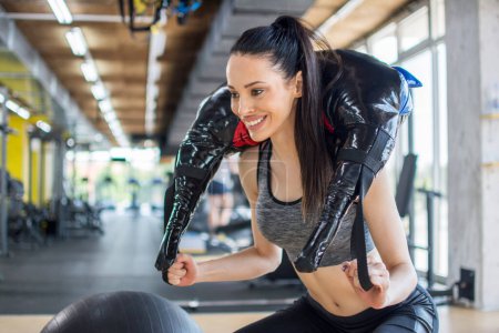 Fitness femme faisant de la musculation avec sac d'exercice sur les épaules et le cou à la salle de gym.