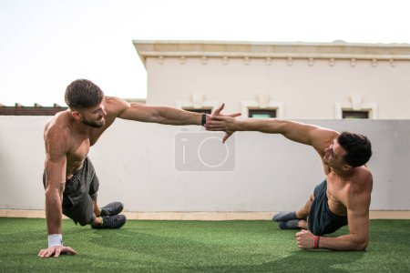 Téléchargez les photos : Deux beaux hommes torse nu musclé donnant haute cinq à l'autre après l'entraînement réussi à la salle de gym sur le toit. - en image libre de droit