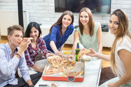 Téléchargez les photos : Groupe de jeunes amis mangeant de la pizza à la maison - en image libre de droit