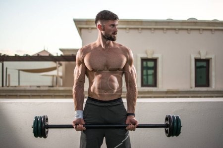 Photo for Shirtless muscular bearded man doing exercises with barbell outdoors. - Royalty Free Image